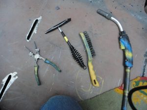 MIG Welding supplies, wire brush, chipping hammer a and MIG welding pliers.